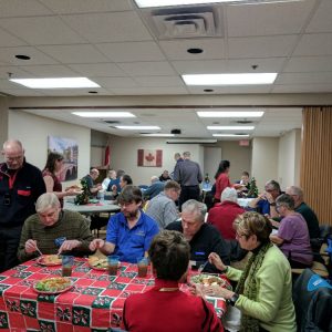 A photograph of our club members having dinner and chatting during our Christmas Potluck in December 2016.