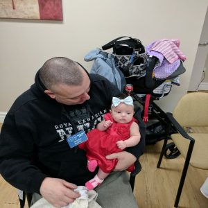 A photograph of one of our North Shore Amateur Radio Club members, Mike (VA3HEM) holding his new baby girl on his lap while she looks around during our Christmas Potluck in December 2016.