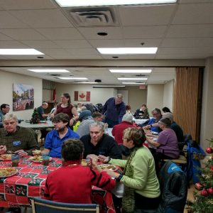 A photograph of our club members having dinner and chatting during our Christmas Potluck in December 2016. 