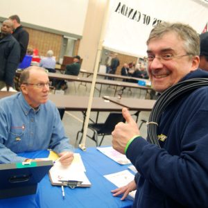 A photograph of an attendee posing and giving a thumbs-up, with a bundle of coax cable of his shoulder, in front of the Radio Amateurs of Canada (RAC) table during the Durham Hamfest.