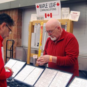 An attendee stops by the Maple Leaf Communication table to speak with a representative and view a product.