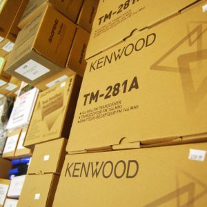 An artistic shot of boxes of the Kenwood TM-281A handheld radio on the Durham Radio vendor table.