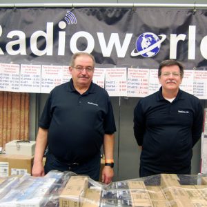 Two representatives of Radioworld pose for a picture at their vendor table in between sales.