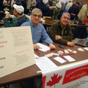 Two representatives of the VA3/VE3 Incoming QSL Bureau pose for a picture at their vendor table.