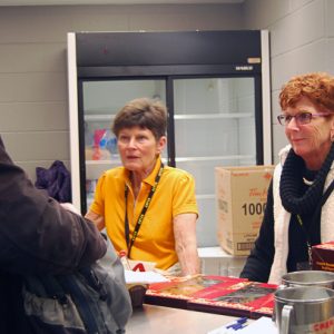 An attendee at the concession stand with Jackie and Colleen, ordering a coffee. 